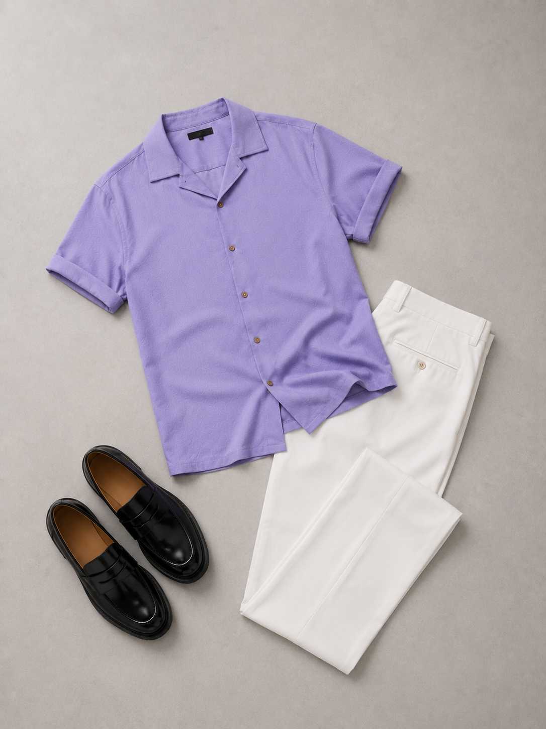 Flat lay men's fashion outfit featuring a lavender short-sleeve button-up shirt, tailored white trousers, and black leather loafers arranged neatly on a clean neutral background with soft shadows. Minimalist smart casual menswear aesthetic perfect for summer and modern gentleman style.